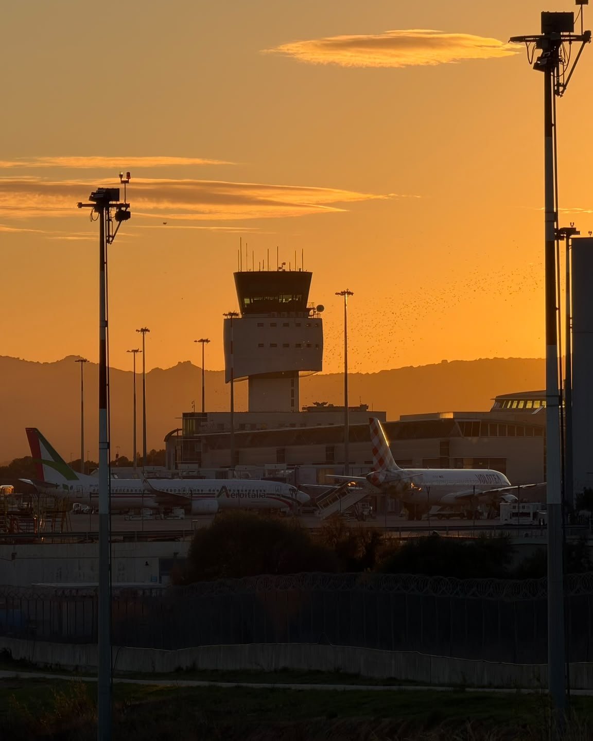Torre di controllo dell'Aeroporto di Olbia al tramonto, con aerei sul piazzale